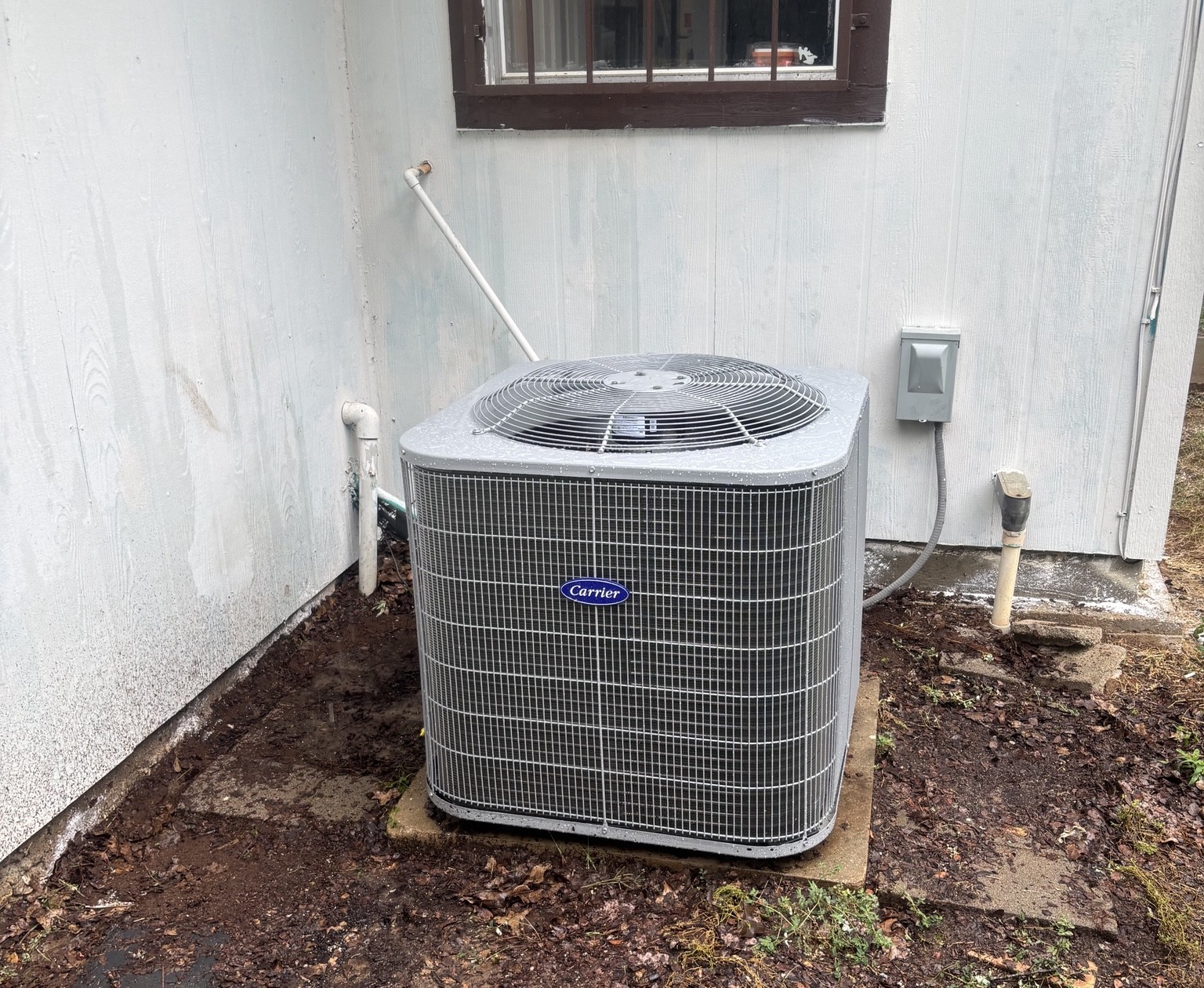 After — new Carrier condenser installed beside the home